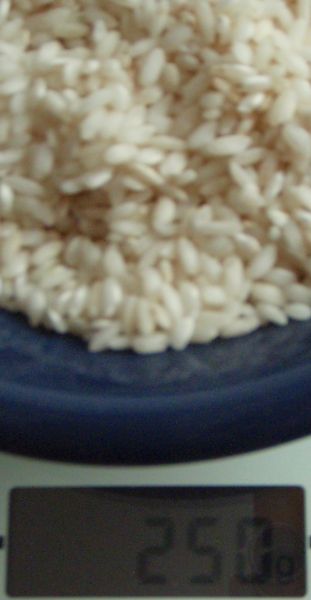 Der Bildausschnitt ist eine Nahaufnahme einer Schale mit Reis auf einer digitalen Waage, die 250 g anzeigt. Der Bildausschnitt ist eine Nahaufnahme einer Schale mit Reis auf einer digitalen Waage, die 250 g anzeigt.